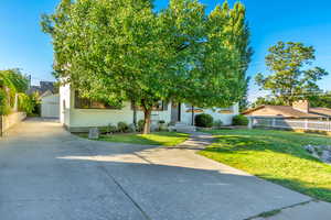 View of property hidden behind natural elements with brick siding, a garage, and concrete driveway