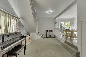 Sitting room with light colored carpet and stairway