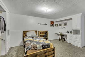 Bedroom with light colored carpet and a textured ceiling