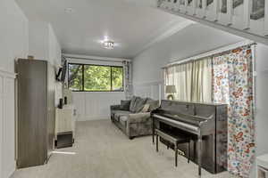 Living area with a decorative wall, a wainscoted wall, and light carpet