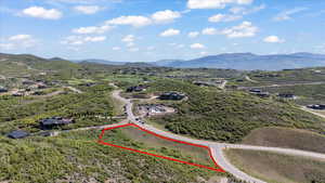 Aerial view of property and surrounding area featuring property boundaries highlighted and a mountain backdrop