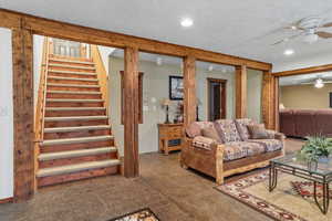 Living room with a textured ceiling, a ceiling fan, stairs, and recessed lighting