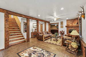 Living area featuring a ceiling fan, a textured ceiling, recessed lighting, a fireplace, and stairway