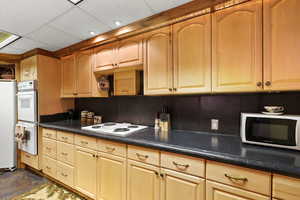 Kitchen featuring a paneled ceiling, dark countertops, and white appliances