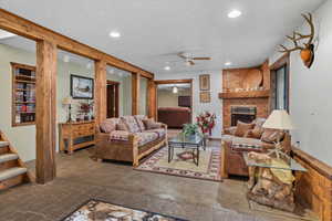 Living room with a ceiling fan, recessed lighting, a brick fireplace, and stairway