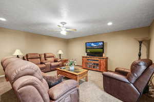 Living area featuring a textured ceiling, ceiling fan, carpet floors, and recessed lighting