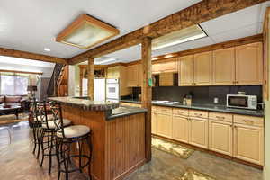 Kitchen featuring a breakfast bar, finished concrete floors, a center island, white appliances, and tile counters