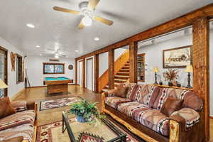 Living area featuring a textured ceiling, billiards, a ceiling fan, recessed lighting, and stairway