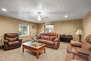 Carpeted living room featuring a textured ceiling, recessed lighting, and ceiling fan