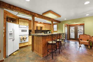 Kitchen featuring white appliances, tile counters, recessed lighting, a breakfast bar, and concrete flooring