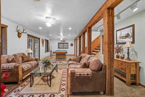 Carpeted living area featuring billiards, a textured ceiling, french doors, ceiling fan, and stairway