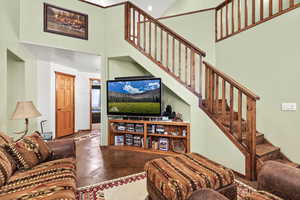 Living room with a towering ceiling, finished concrete flooring, and stairway