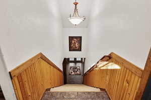 Stairway featuring high vaulted ceiling and a textured wall