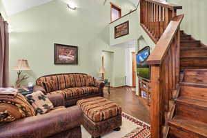 Living area with high vaulted ceiling, finished concrete floors, and stairs