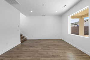 Empty room featuring stairs, wood finished floors, and recessed lighting