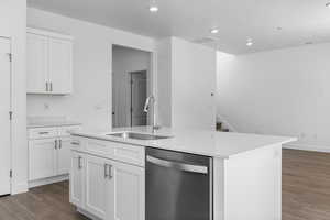 Kitchen featuring stainless steel dishwasher, white cabinetry, an island with sink, dark wood-type flooring, and recessed lighting