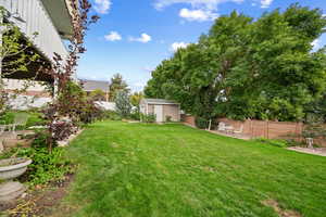 Fenced backyard featuring a patio and a shed