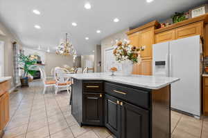Kitchen with white refrigerator with ice dispenser, light tile patterned floors, recessed lighting, light stone counters, and decorative light fixtures