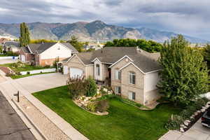 Single story home featuring brick siding, a mountain view, a front yard, and driveway
