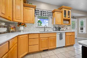 Kitchen with light tile patterned floors, white dishwasher, healthy amount of natural light, and tasteful backsplash