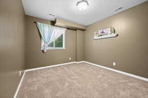 Carpeted empty room with baseboards and a textured ceiling