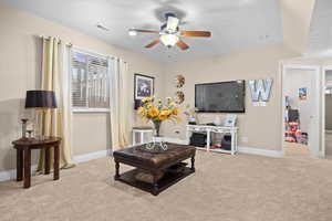 Living area with light carpet and a ceiling fan