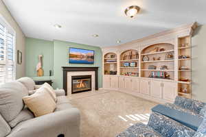 Living area featuring a fireplace, a textured ceiling, light colored carpet, and built in shelves