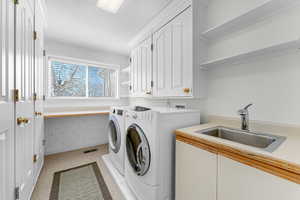 Laundry room with wallpapered walls, separate washer and dryer, and cabinet space