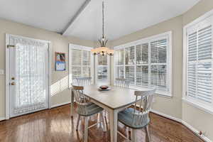 Dining room with wood-type flooring, beamed ceiling, and a chandelier