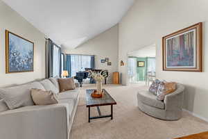 Living room featuring carpet floors, high vaulted ceiling, and a skylight