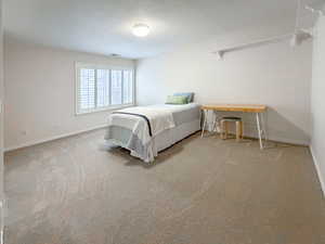 Bedroom featuring a textured ceiling and light colored carpet