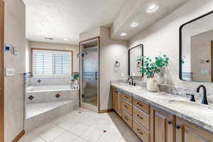 Full bathroom featuring double vanity, a shower stall, a bath, light tile patterned floors, and recessed lighting