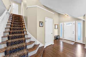 Foyer featuring dark wood-type flooring, a towering ceiling, and stairs