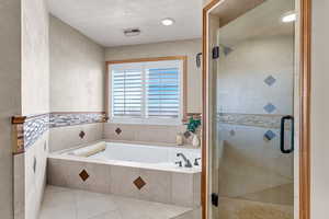 Bathroom featuring a garden tub, a shower stall, tile patterned floors, and recessed lighting
