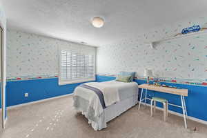 Carpeted bedroom featuring wallpapered walls and a textured ceiling
