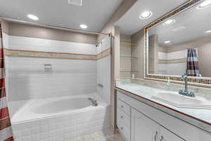 Bathroom featuring tiled shower / bath, vanity, recessed lighting, and light tile patterned floors