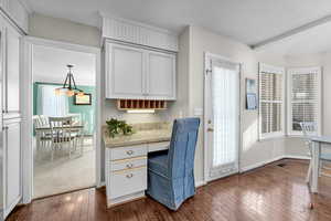 Office space featuring built in desk, dark wood-style flooring, healthy amount of natural light, and beamed ceiling