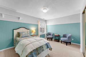 Bedroom featuring a textured ceiling, wainscoting, and carpet