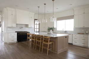 Kitchen featuring backsplash, range with two ovens, white cabinetry, a center island, and recessed lighting