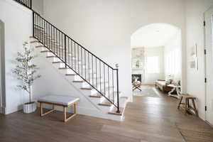 Stairway with wood finished floors, a stone fireplace, and arched walkways