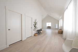 Bonus room with light wood-style flooring and high vaulted ceiling