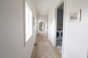 Corridor featuring light wood-type flooring and washer and clothes dryer