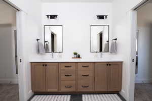 Bathroom with double vanity and dark colored carpet