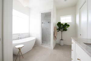 Full bathroom featuring vanity, a freestanding tub, a marble finish shower, and tile walls