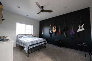 Carpeted bedroom with ceiling fan and an accent wall