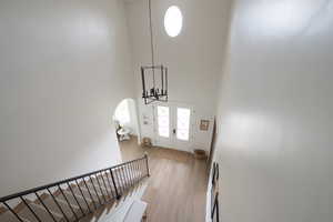 Stairs featuring a high ceiling, arched walkways, wood finished floors, french doors, and a chandelier