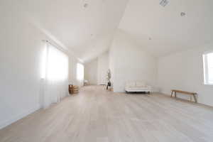 Additional living space with high vaulted ceiling and light wood-style floors