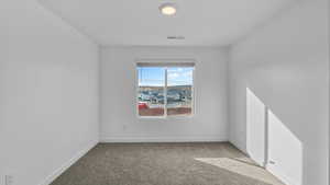 Empty room with light colored carpet and baseboards