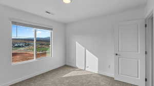 Unfurnished bedroom with light carpet and baseboards