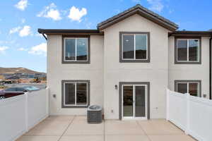 Back of house with stucco siding, a mountain view, and a patio
